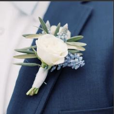 a boutonniere with white flowers and greenery is worn on the lapel of a man