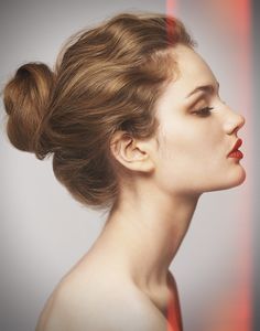 a woman with her hair in a high bun is looking to the side and has red lines behind her