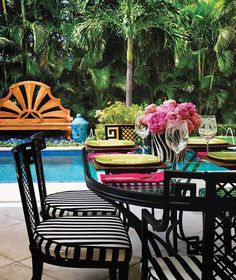 an outdoor dining table and chairs near a pool