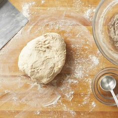 a ball of dough sitting on top of a wooden table next to a measuring spoon