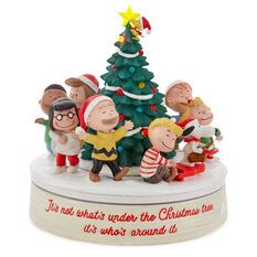 a group of figurines standing next to a christmas tree