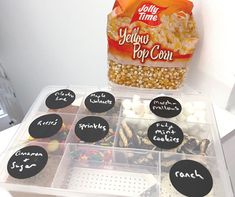 a plastic container filled with lots of different types of candies next to a bag of popcorn