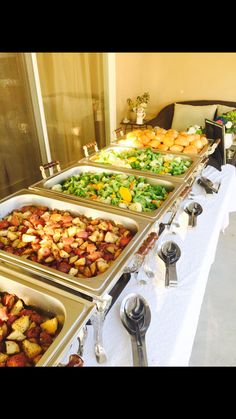 several trays of food are lined up on a buffet table