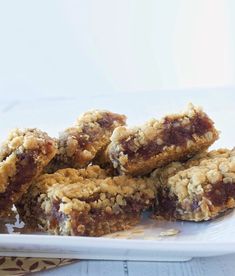 a white plate topped with cookies and bars on top of a wooden table next to a cup