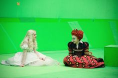 two women in costumes sit on the ground and look at each other as they talk