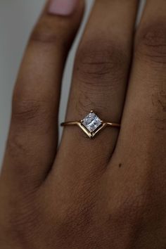 a woman's hand with a diamond ring on top of her finger and the other hand holding it