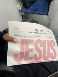 a person holding up a paper with the word jesus printed on it