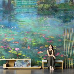 a woman sitting on a bench in front of a wall mural with water lillies