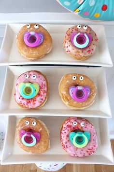 four donuts with faces and eyes on them in white trays next to each other