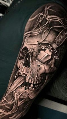 a man's arm with a black and grey tattoo design on it, featuring a skull