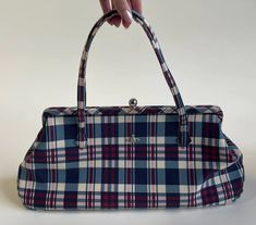 a hand holding a blue and white plaid purse on a white background with room for text