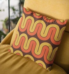 an orange and brown pillow sitting on top of a yellow chair