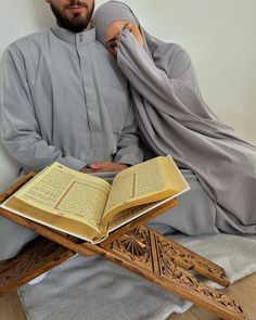 a man sitting on the floor with an open book in front of him and wearing a gray outfit