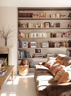 a living room filled with lots of furniture and bookshelves next to a fire place