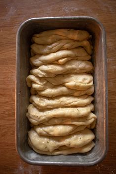 a metal pan filled with dough on top of a wooden table