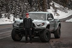 a man standing next to a silver truck