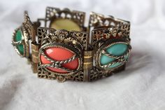 This item is a multi-color, vintage bracelet with an ornate, brass pattern and hinged clasp. The colors are emerald green, sky blue, coral, amber brown and light yellow. Good condition, no missing stones, unbranded. Feel free to reach out with any questions on this item. Vintage Multicolor Bracelets For Formal Occasions, Ornate Multicolor Bracelets For Gifts, Ornate Multicolor Bracelet For Gift, Multicolor Vintage Decorative Jewelry, Vintage Multicolor Decorative Jewelry, Vintage Handmade Multicolor Bracelets, Vintage Multicolor Bracelets, Vintage Green Bracelet With Patina, Vintage Multicolor Jeweled Bracelets