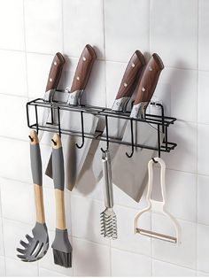 a rack with utensils hanging from it's side on the wall next to a tiled wall