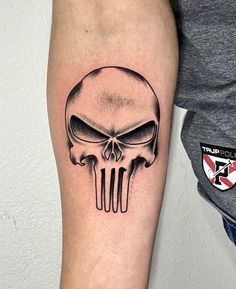 a black and white skull tattoo on the arm