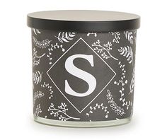 a black and white candle with the letter s on it's lid, in front of a white background