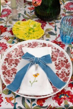 a plate with a blue bow on it sitting next to a glass vase filled with flowers