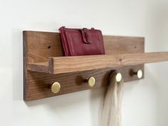 a wooden shelf with two purses hanging from it's hooks on the wall