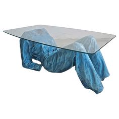 a glass table with a blue cloth draped over it's body and legs on the ground