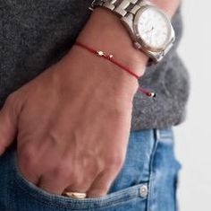 a close up of a person wearing a watch on their wrist with a red string