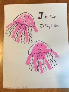 two pink jellyfish handprints on white paper with the letter j is for jellyfish