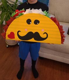 a little boy holding up a paper plate with a mustache on it