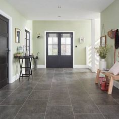 an empty hallway with black doors and gray tile flooring on the walls, along with potted plants