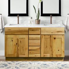 two mirrors are above the double sink vanity in this bathroom with white walls and wood cabinetry