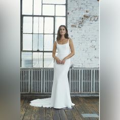 a woman in a white wedding dress posing for a photo on a wooden floor next to a brick wall