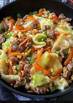 a skillet filled with meat and vegetables on top of a blue table cloth next to chopsticks