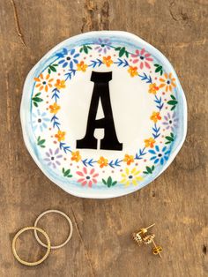 a plate with the letter a on it next to two wedding rings and a ring holder