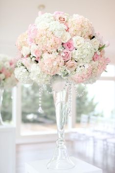 a vase filled with pink and white flowers on top of a table next to another vase