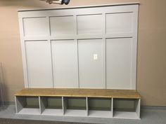 an empty room with some white cabinets and wooden bench on the floor next to it