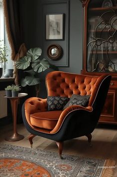 an orange chair sitting on top of a wooden floor next to a table with a potted plant