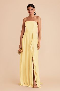 a woman wearing a yellow strapless bridesmaid dress and holding a bouquet in her hand