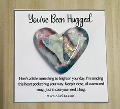 a heart shaped brooch sitting on top of a piece of paper with the words you've been hugged