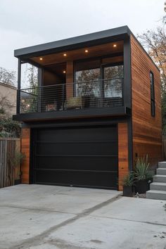 a two story house with black garage doors and wood sidings on the side of it