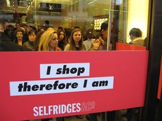 a group of people standing in front of a red sign that says i shop there before i am