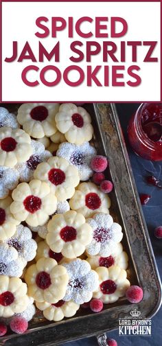 a pan filled with jam spritz cookies covered in powdered sugar