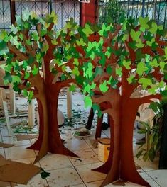 two paper trees with green leaves on them in a room filled with chairs and trash cans