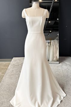 a white wedding dress on display in front of a mirror