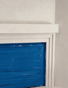 a white fireplace with blue paint on it