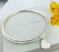 "Please see expected delivery dates. For eye catching sparkle and elegance, this pretty set of 2 silver stacking bangles with a dangling silver heart, make the perfect present to celebrate any occasion or just to say thank you Handcrafted in my UK workshop from sterling silver, the bangles have a combined width of 4mm and a lovely textured finish to enhance their sparkle  SMALL    60mm diameter ,   190mm   or 7 1/2\" circumference MEDIUM 65mm diameter ,   204mm   or 8\" circumference LARGE     68mm diameter ,   218m      or 8 3/4 circumference Recent review : \"    Bought for my best friend as part of a bridesmaid gift. A subtle and classy piece that can be worn every day. This was a last minute addition to the gift with the added difficulty of postal strikes however Anne was great and des Silver Bangle For Valentine's Day Gift, Silver Heart Bracelet For Birthday, Silver Heart Bracelet For Birthday Gift, Stacking Bangles, The Bangles, Bangles Set, Stacked Bangles, Bangle Set, Personal Message