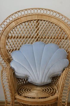 a wicker chair with a blue pillow on it's back and seat cushion