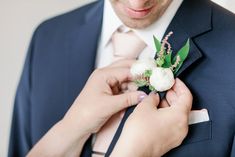 a man in a suit adjusting his boutonniere