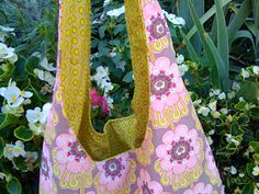 a pink and yellow flowered bag sitting in front of some flowers